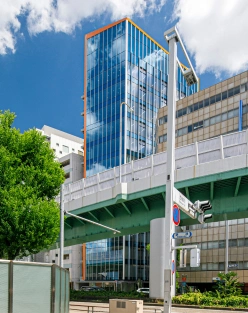 NOBUNAGAビルの外観。ビルの上辺にあるオレンジラインが青空の下輝いている。