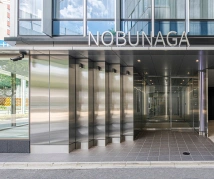 NOBUNAGAビルのエントランス。シルバーの英語が自動ドアの上に配置されている。
